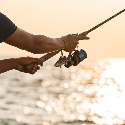 The ReelFresh freshener swinging from a reel as a fisherman casts into the low sun